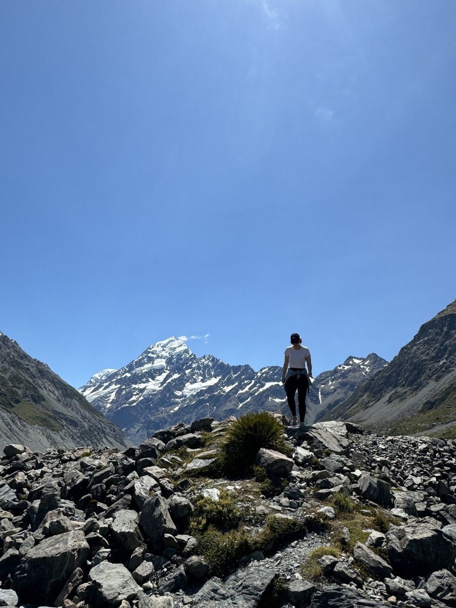 Julia standing on rocks in the Hooker Valley, with Aoraki/Mount Cook in the background