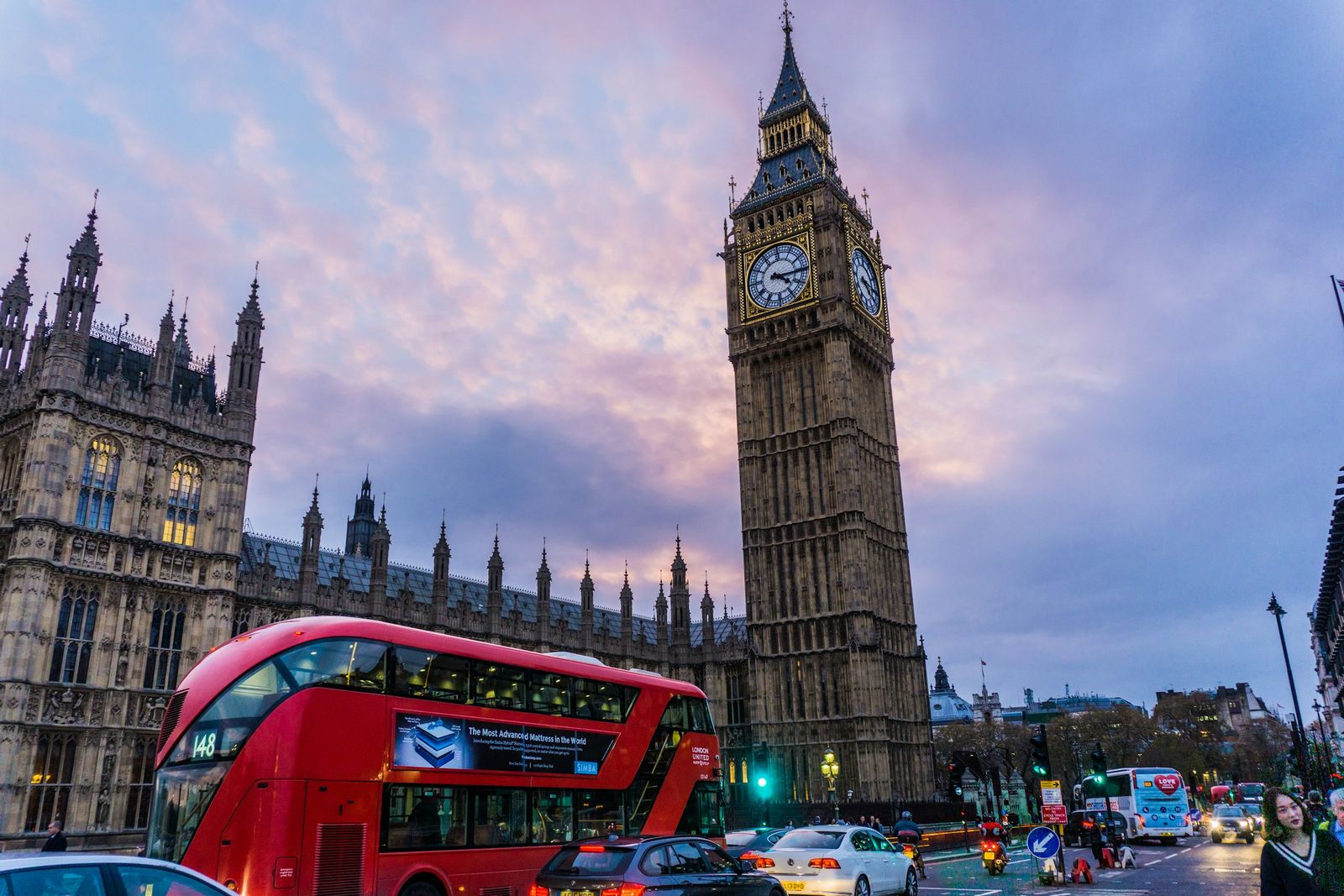 Big Ben and the Houses of Parliament in London at dusk, with a red double-decker bus