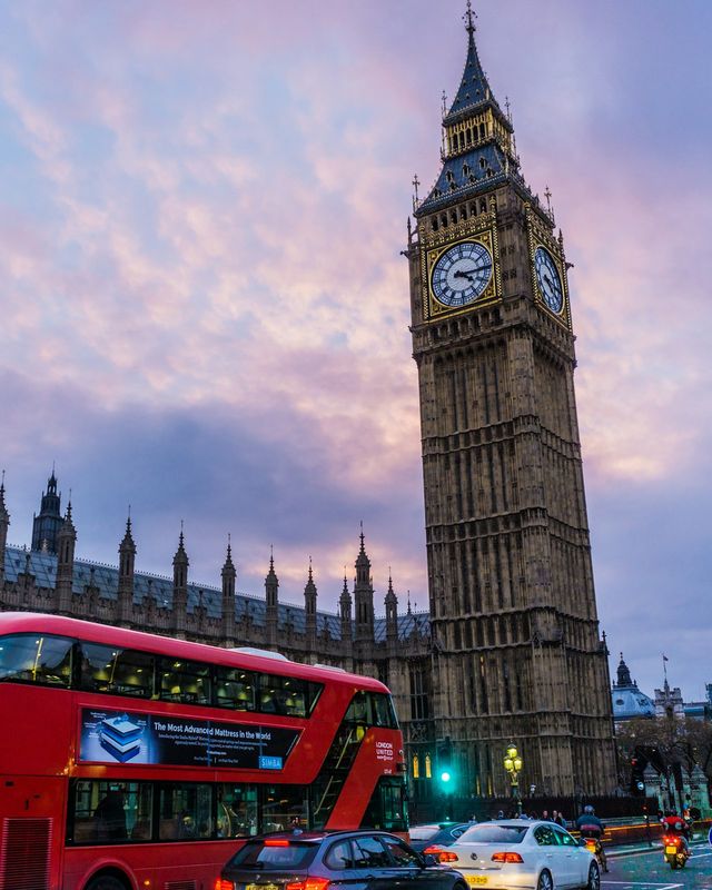Big Ben and the Houses of Parliament in London at dusk, with a red double-decker bus